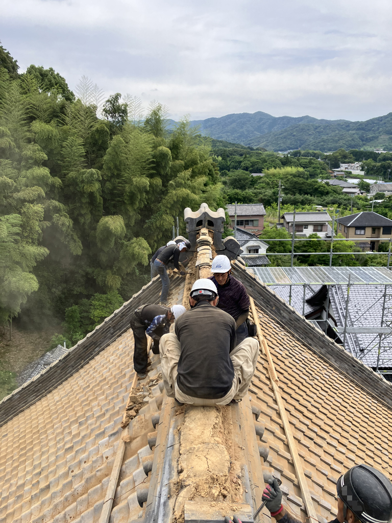 屋根リフォーム中の画像。瓦屋根の上で職人が作業している。