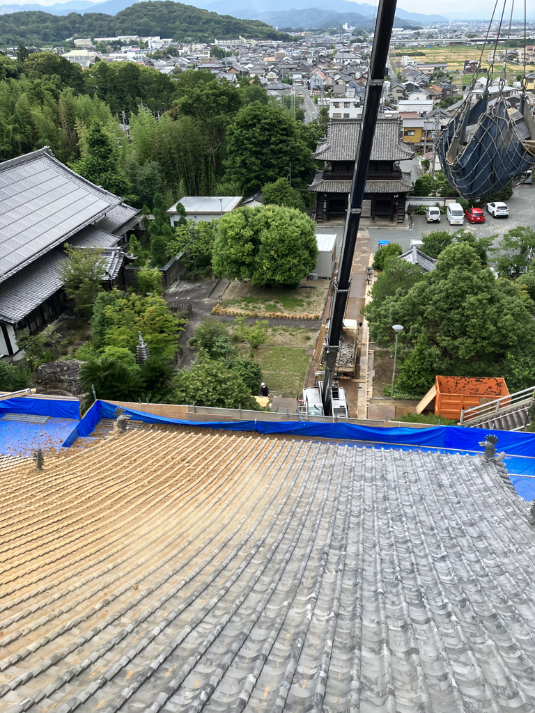 屋根リフォーム中の画像。瓦屋根の上から寺院を見下ろしている。