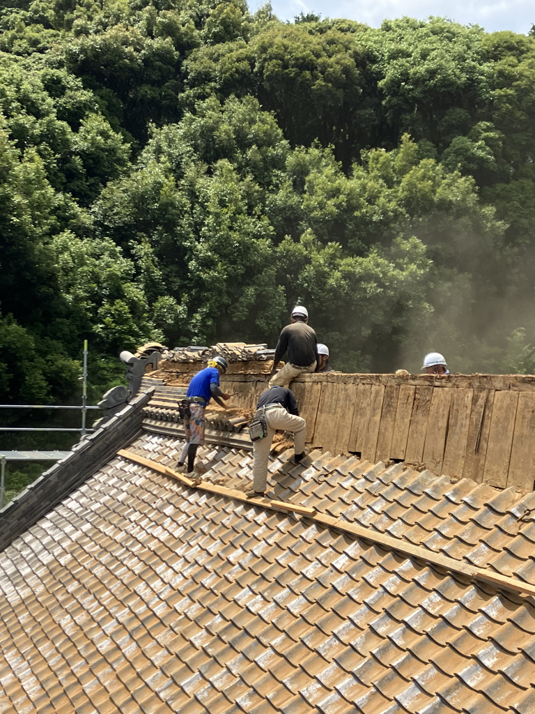 屋根リフォーム中の画像。瓦屋根の上で職人が作業している。